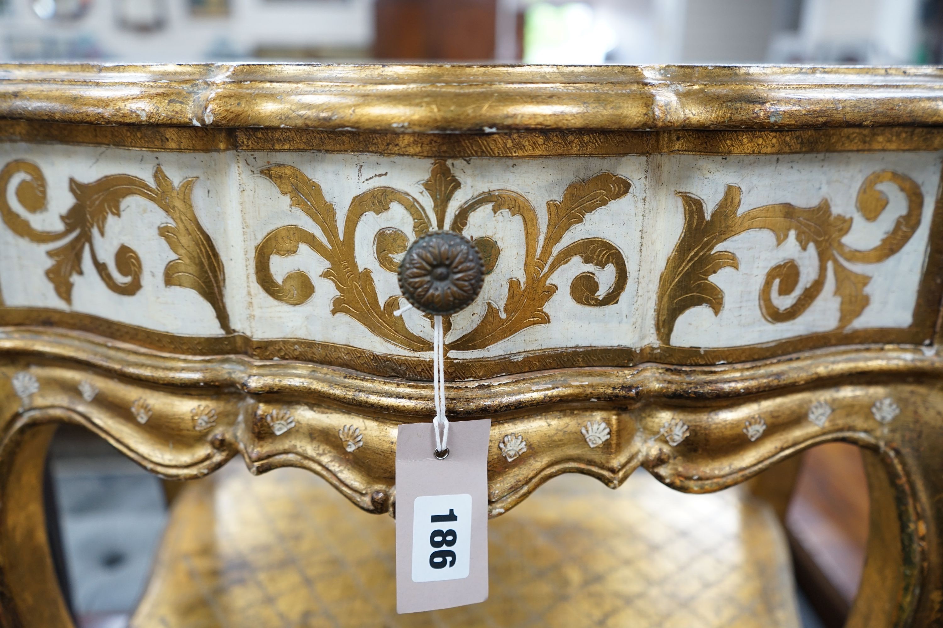 A Florentine gilt and cream painted serpentine two tier side table, width 50cm, depth 34cm, height 58cm